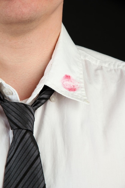 Beijo de batom na gola da camisa do homem isolado em preto