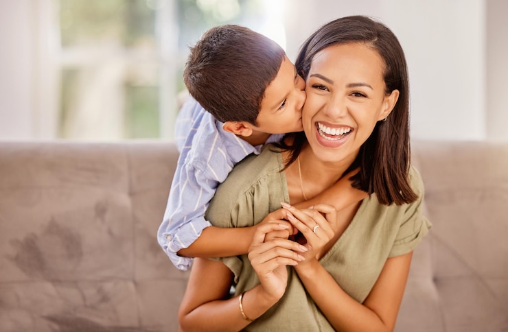 Foto beijo mãe e filho com abraço de amor, carinho e gratidão no dia das mães no sofá da sala de sua casa retrato de uma jovem feliz e mãe com um sorriso de carinho de seu filho