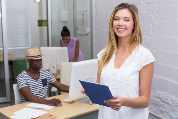 Beiläufige Frau mit dem Kollegen, der hinten Computer im Büro verwendet