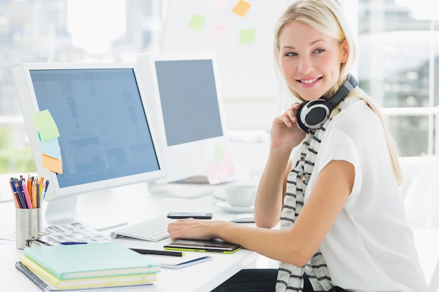 Foto beiläufige frau mit kopfhörer am computertisch im büro