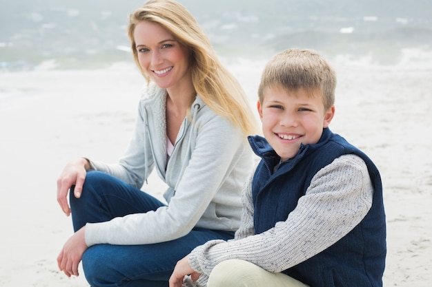 Beiläufige Frau und Sohn, die am Strand sich entspannt