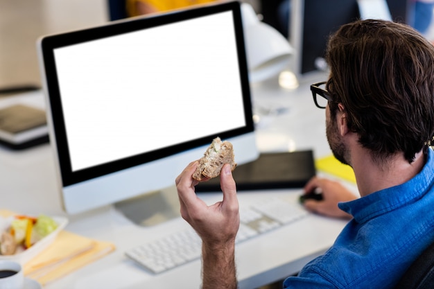 Beiläufiger Geschäftsmann, der ein Sandwich isst