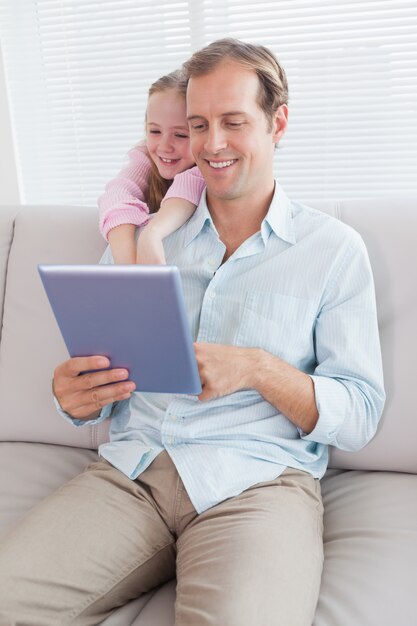 Beiläufiger Vater und Tochter, die Tablette auf der Couch verwendet