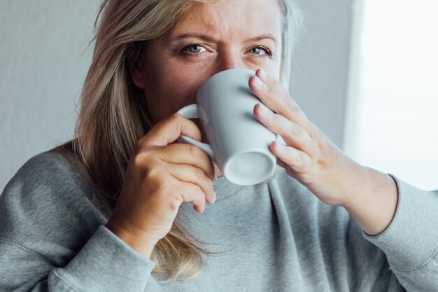 Foto beiläufiges porträt einer großen, jungen, hübschen frau, die kaffee trinkt, städtisches porträt