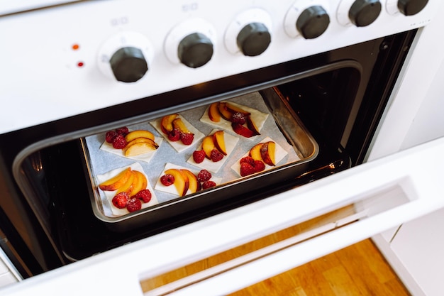 Beim Blick in den Ofen prüfen wir die Bereitschaft der gebackenen Süßgebäcke. Offene Ofentür mit süßen Torten mit f