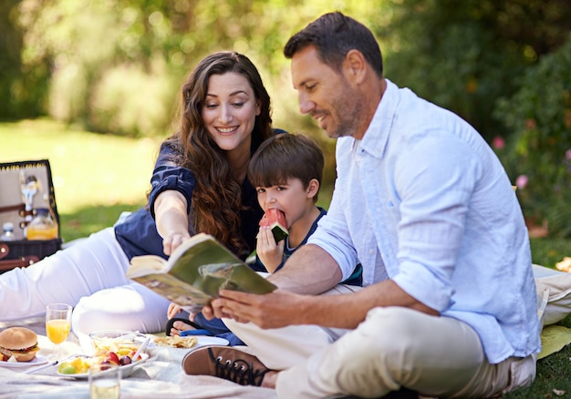 Beim Picknick eine Geschichte lesen Aufnahme einer Familie, die gemeinsam ein Picknick genießt