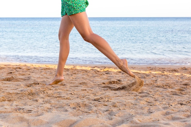 Bein der Frau, die auf Sandstrand-Sommerferien läuft Glückliche schöne Frau, die auf den Strand läuft