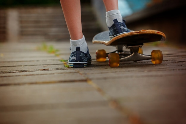 Beine auf dem Skateboard nah oben auf der Straße am sonnigen Tag