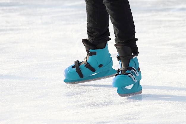 Beine beim blauen Schlittschuhlaufen auf der Eisbahn. Sport, Hobbys und Erholung aktiver Menschen