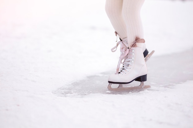 Beine des kleinen Mädchens, das im Morgenlicht im Morgengrauen auf Eis läuft. Wintersport