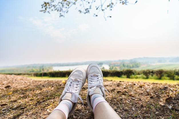 Beine des Reisenden, der auf der schönen Natur des Parks sitzt