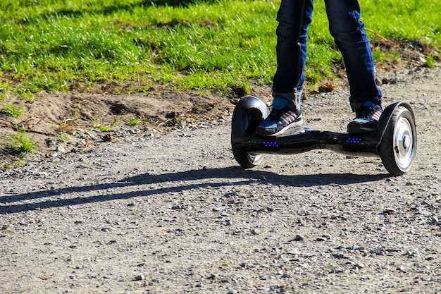 Beine eines Jungen, der auf einem selbstbalancierenden Mini-Hoverboard in der Stadt reitet