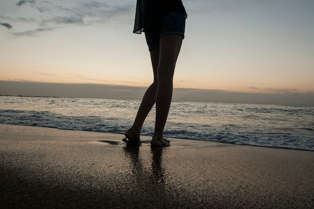 Beine eines jungen Mädchens am Meer und Sandstrand