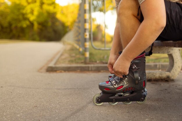 Beine eines jungen Mannes, der Rollschuhen im Park trägt