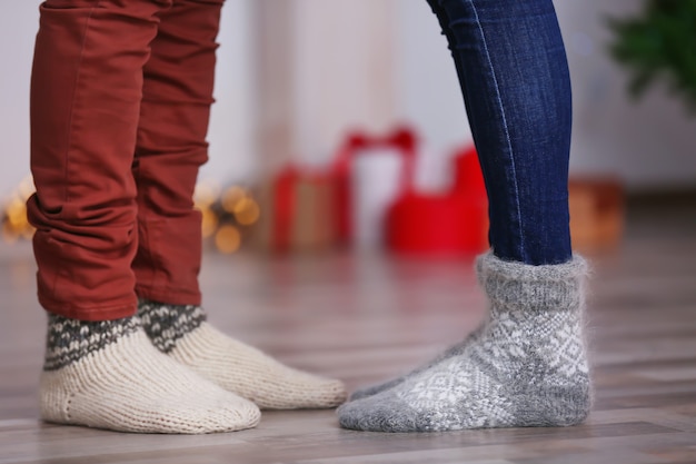 Beine eines jungen Paares in warmen Socken zu Hause. Weihnachtskonzept