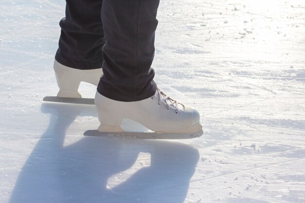 Beine eines Mädcheneislaufens auf einer Eisbahn. Hobbys und Freizeit. Wintersport