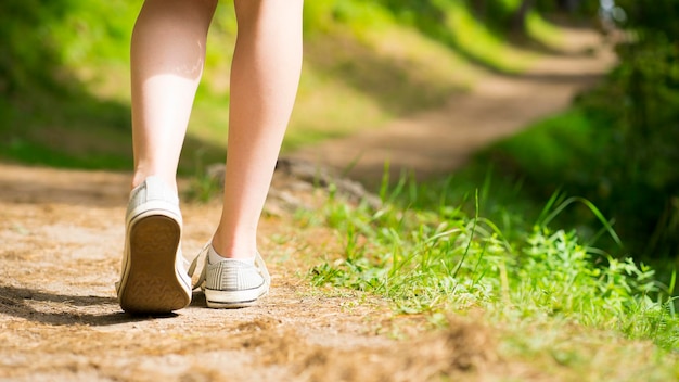 Beine eines Mädchens, das einen Weg im Wald entlang geht