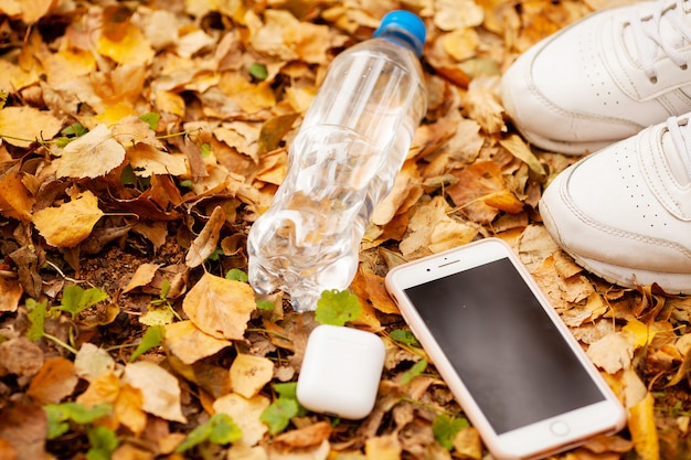 Beine eines Mädchens in den weißen Turnschuhen im Herbstlaub