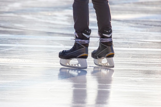 Beine eines Mannes, der auf einer Eisbahn Schlittschuh läuft. Hobbys und Sport. Urlaub und Winteraktivitäten.