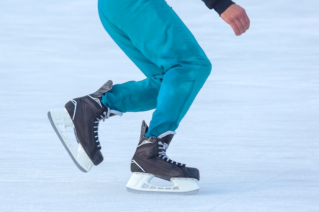 Beine eines Mannes, der auf einer Eisbahn Schlittschuh läuft. Hobbys und Sport