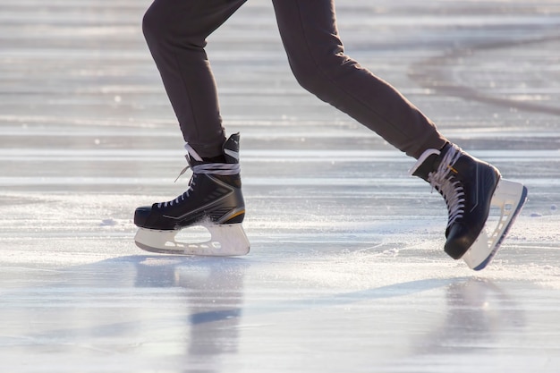 Beine eines Mannes, der auf einer Eisbahn Schlittschuh läuft. Hobbys und Sport