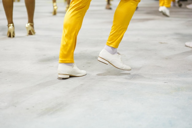 Beine eines Sambista-Tanzes mit gelber Hose und weißen Schuhen im Sambodromo da Marques de Sapucai in Rio de Janeiro