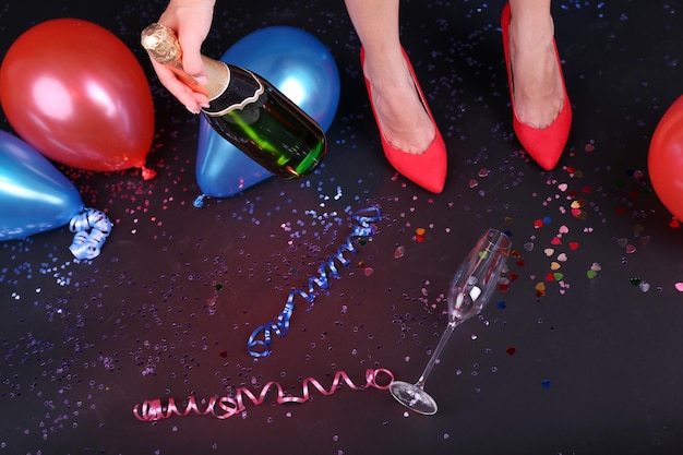 Foto beine mit konfetti-champagner und luftballons auf dem boden