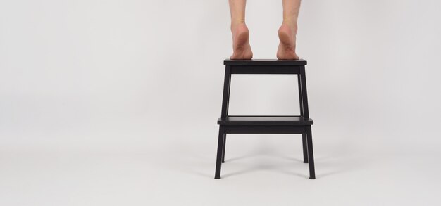 Beine und barfuß Zehenspitzen auf Tritthocker oder Holztreppen auf weißem Hintergrund.