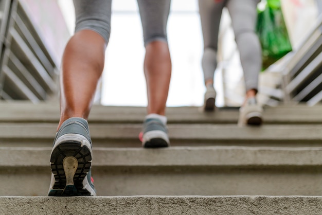 Beine und Schuhe eines Joggers, der eine Treppe hinauf läuft