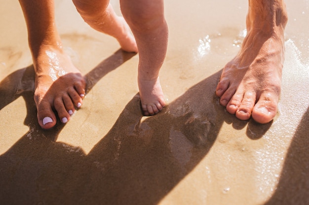 Beine von Eltern und Kind auf Sand Glückliches liebevolles Familienkonzept family