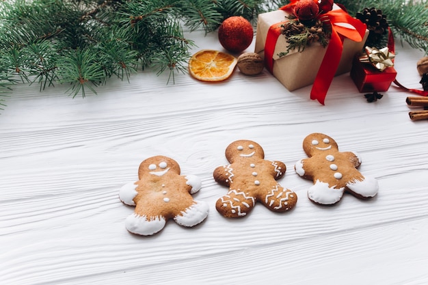 Beira de natal. bolinhos de gengibre, especiarias e decorações em fundo de madeira branca.