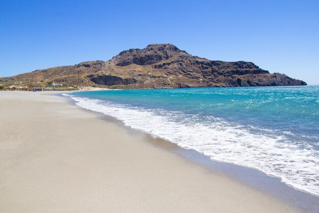 Beira-mar com praia de areia e água azul transparente na ilha de Creta, na Grécia