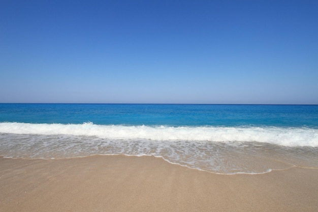 Beira-mar de areia com céu azul e água