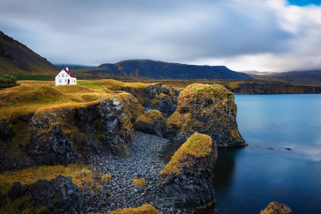 Beira-mar na Islândia com falésias e uma pequena casa na aldeia de Arnarstapi