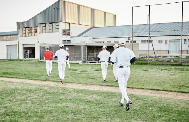 Beisebol esportivo e equipe correndo no campo para um exercício de partida ou treinamento em um estádio Softbol de fitness e grupo de atletas do sexo masculino se preparando para treino de jogo ou prática em um campo na arena