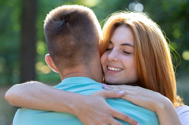 Bela adolescente com cabelo vermelho brilhante, abraçando o namorado ao ar livre. primeiro amor e relacionamento romântico.