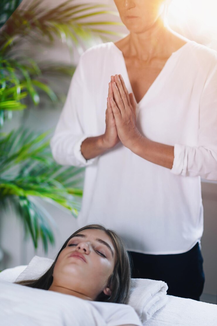 Foto bela adolescente deitada com os olhos fechados e recebendo tratamento de cura reiki reiki praticante de pé e rezando acima do corpo do paciente