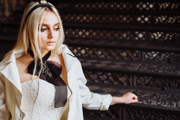 Foto bela adolescente vestindo vestido de noiva enquanto está sentada nas escadas