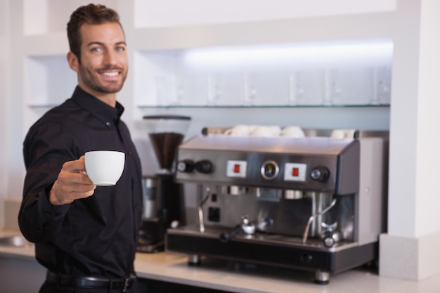 Foto bela barista oferecendo uma xícara de café à câmera