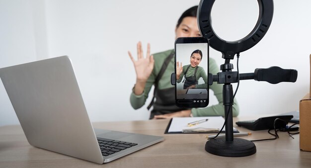 Bela blogueira asiática na frente da câmera para gravar vídeo vlog em streaming ao vivo em sua loja Negócio on-line influenciador em conceito de mídia social Venda on-line Compras on-line