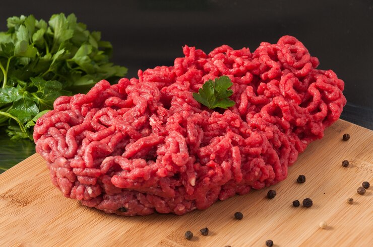 Foto bela carne picada crua decorada com ervas em uma tábua de madeira