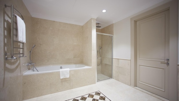 Bela casa de banho em estilo moderno com paredes de azulejos cinza Há uma banheira branca com uma divisória de vidro espelhos pia luz vaso sanitário e um bidê lâmpadas luminosas