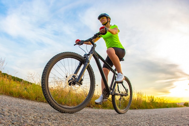 Bela ciclista atlética anda de bicicleta na estrada tendo como pano de fundo a natureza