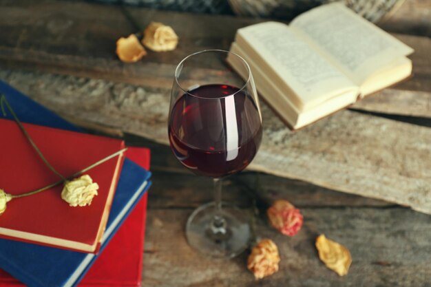 Bela composição com copo de vinho com livros antigos na mesa close-up