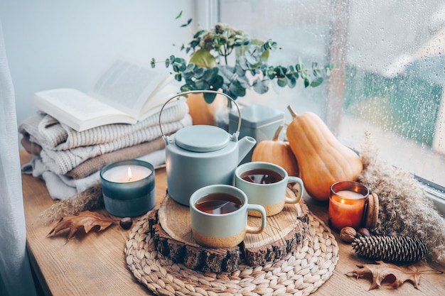 Bela composição de outono com velas acesas e xícara de chá no peitoril da janela