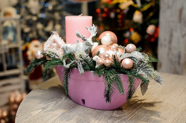 Bela composição decorativa de mesa de Natal com vela, veado de brinquedo, bolas de vidro e abeto em vaso rosa