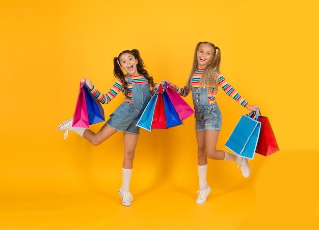 Bela compra. conceito de consumidor comprador. economia de compra de férias. sacolas de compras pesadas para crianças pequenas. grande venda de presentes. crianças viciadas em compras felizes. pacotes de cuidados de meninas. salto livre. compras de verão.