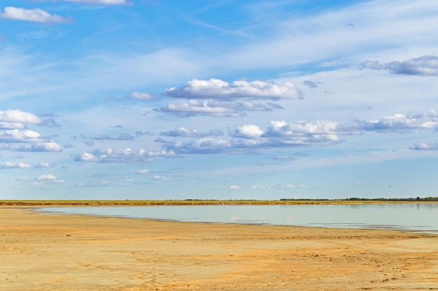 Foto bela costa do lago nuvens brancas na superfície da água do céu e praia de areia cena de natureza tranquila