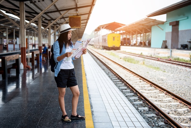 Bela dama olha para o mapa enquanto aguarda o trem na estação.