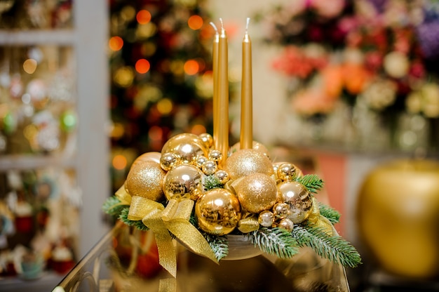 Bela decoração de mesa de natal feita de velas douradas, bolas de vidro e ramos de abeto